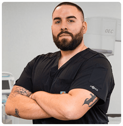 Man in black scrubs with arms crossed.